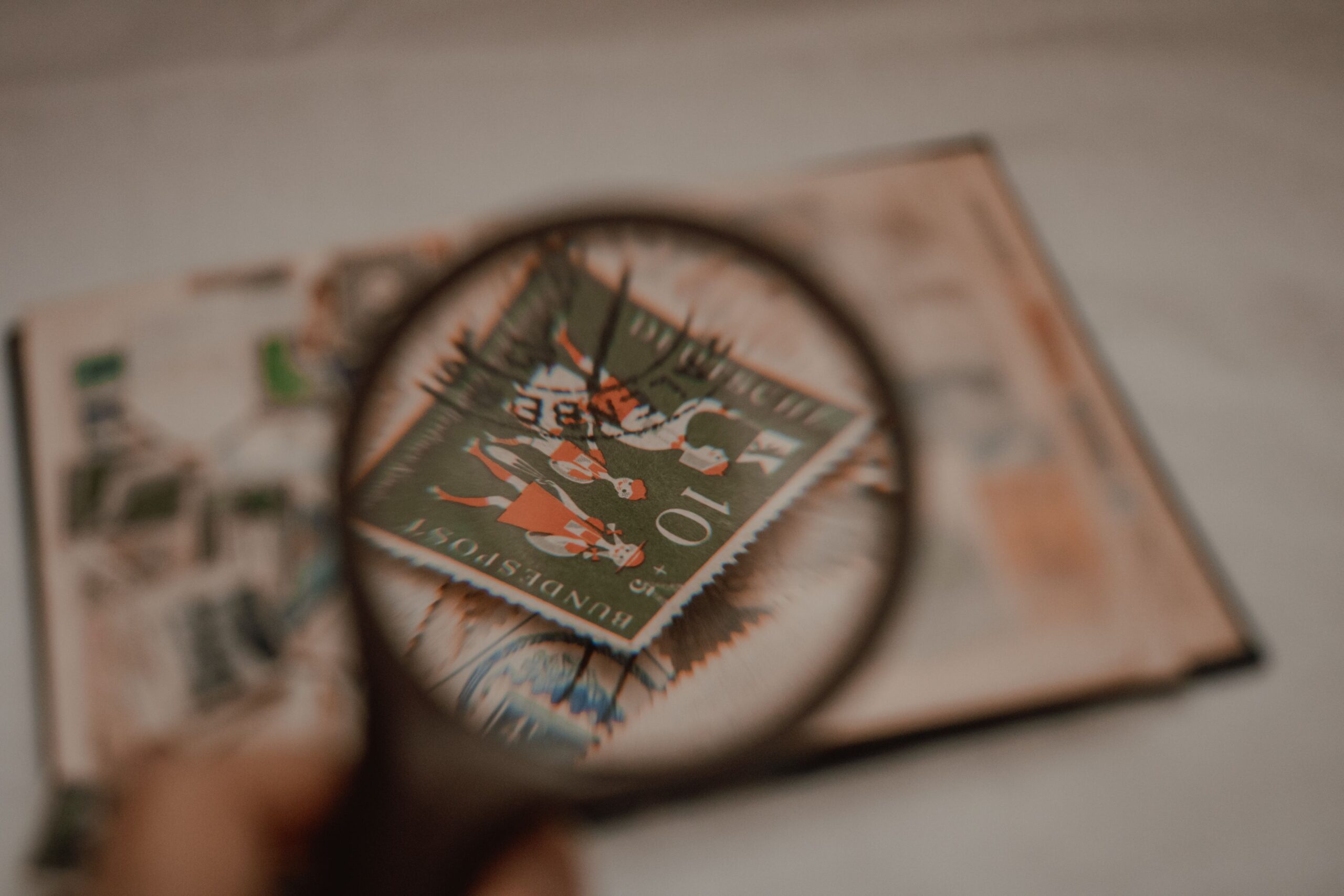 Vintage stamp inspected under a magnifying glass for authentication