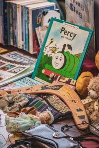 A diverse array of collectibles spread out on a table - trading cards, vintage toys, coins, and comic books