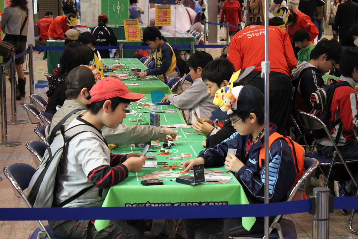 Two players engaged in a Pokémon Trading Card Game battle at a table with cards spread out