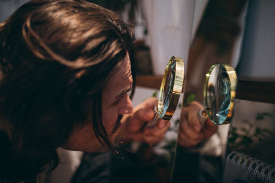 Person examining a trading card with a magnifying glass