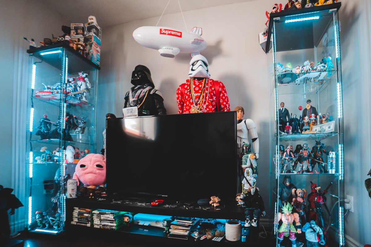 Assorted collectible figurines displayed on a shelf with TV