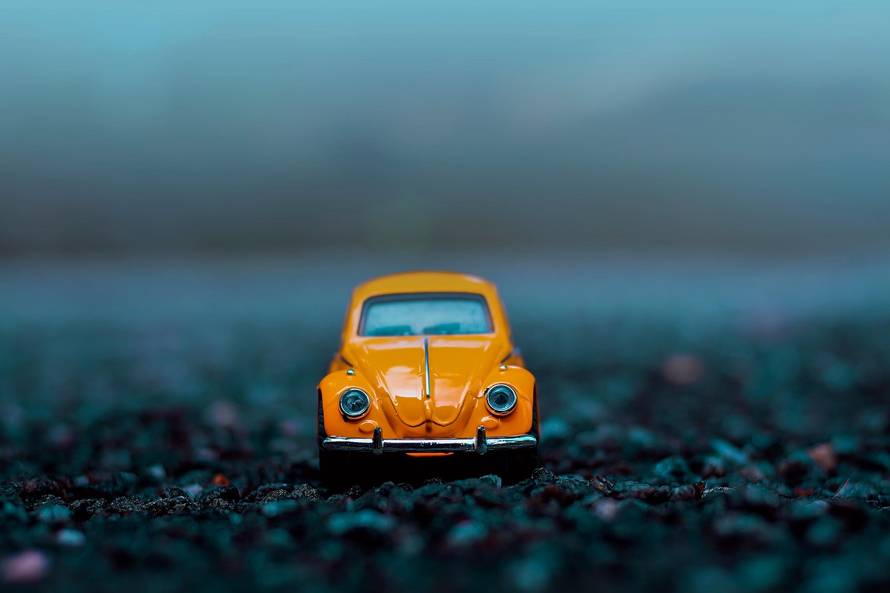 Die-cast car on a clean white surface with magnifying loupe and soft brush for grading inspection