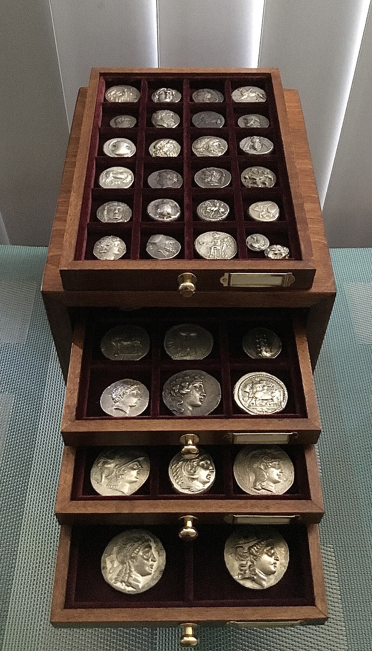 Wooden coin cabinet with trays holding ancient silver coins
